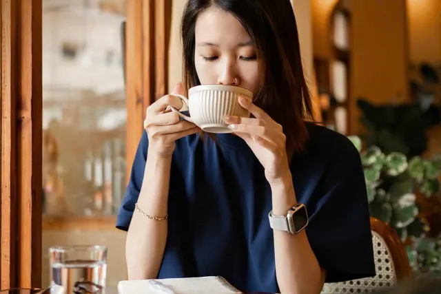 Cô gái nhấp ngụm cà phê nóng bên cửa sổ