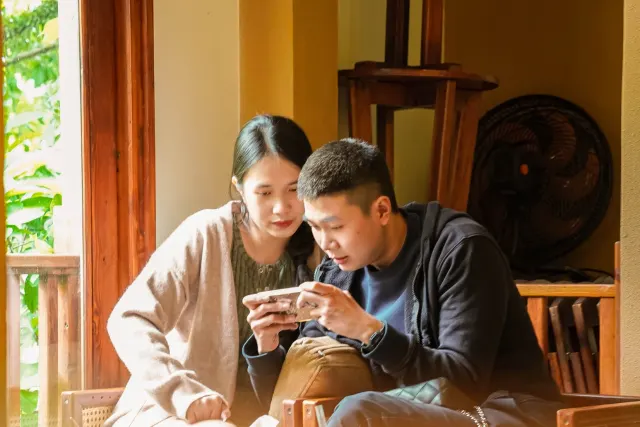 Một cặp đôi cùng xem điện thoại trong góc quán