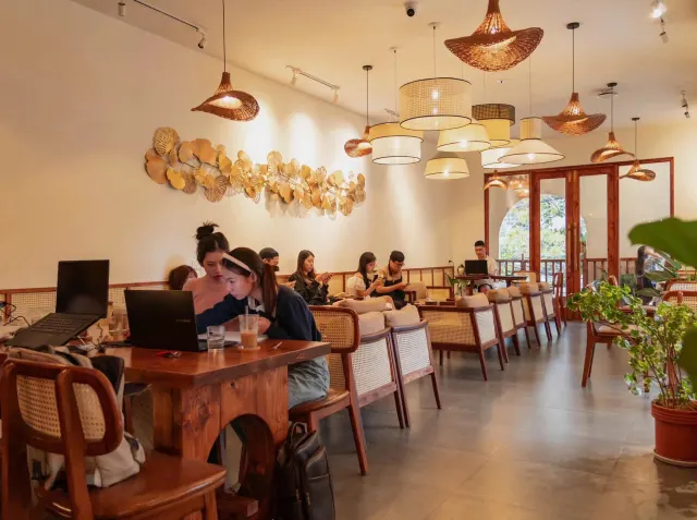 Gian trong nhà với đèn mây, bàn gỗ và bảng hiệu Cafeholic
